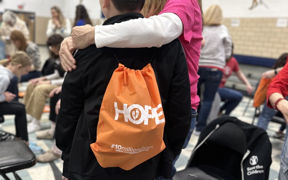 Wearing new socks and shoes, a student takes home his old socks and shoes in a new Hope Tote.