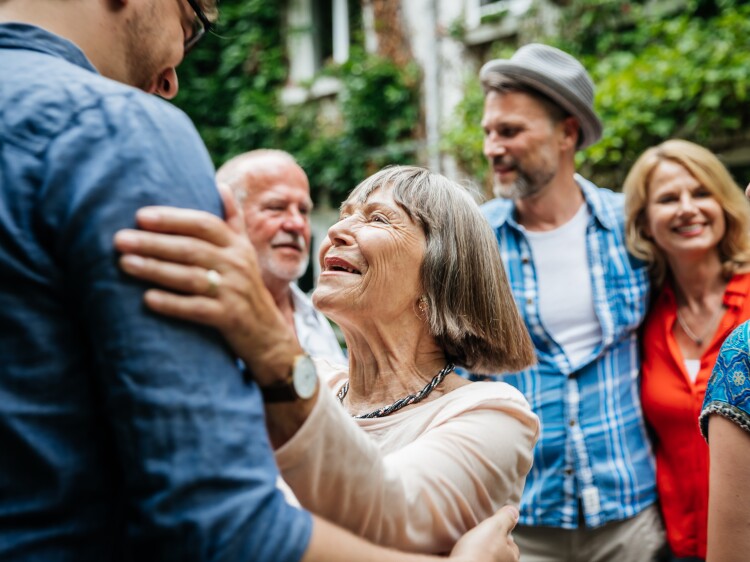 An elderly lady greeting some of her family members in a courtyard before a family meal.