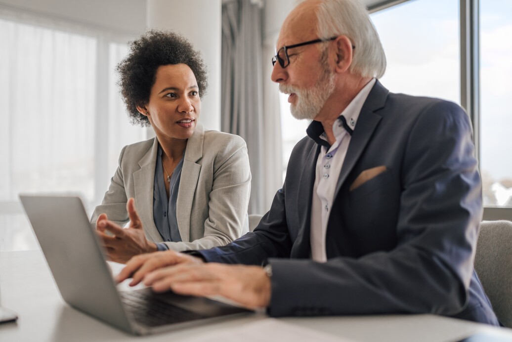 Male and female coworkers talking over a computer