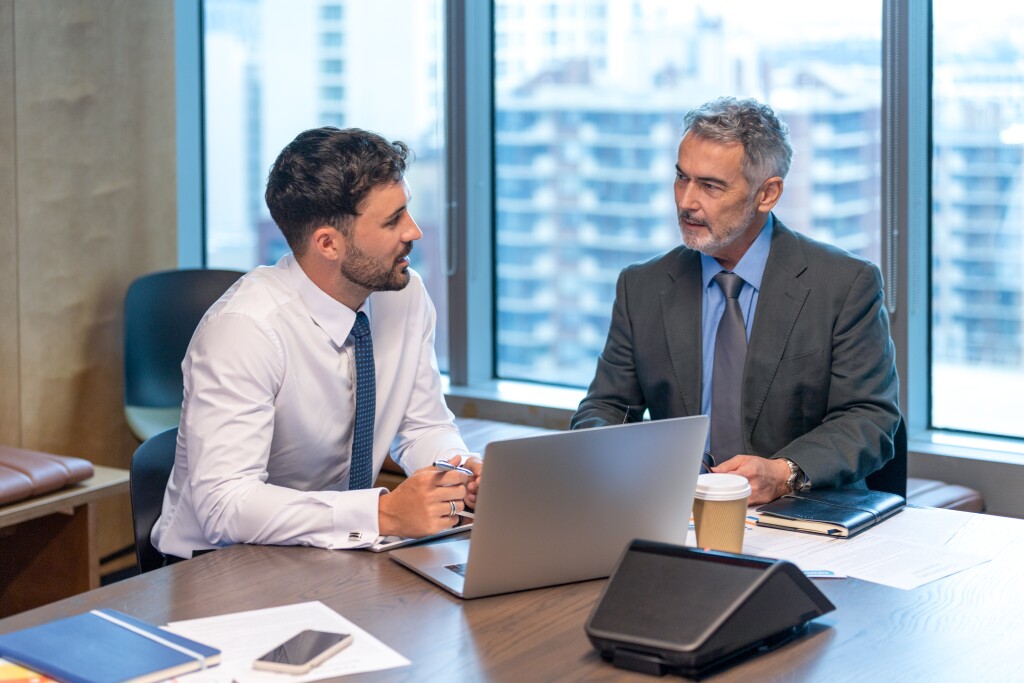 Two business men talking and working on a laptop computer in the office.