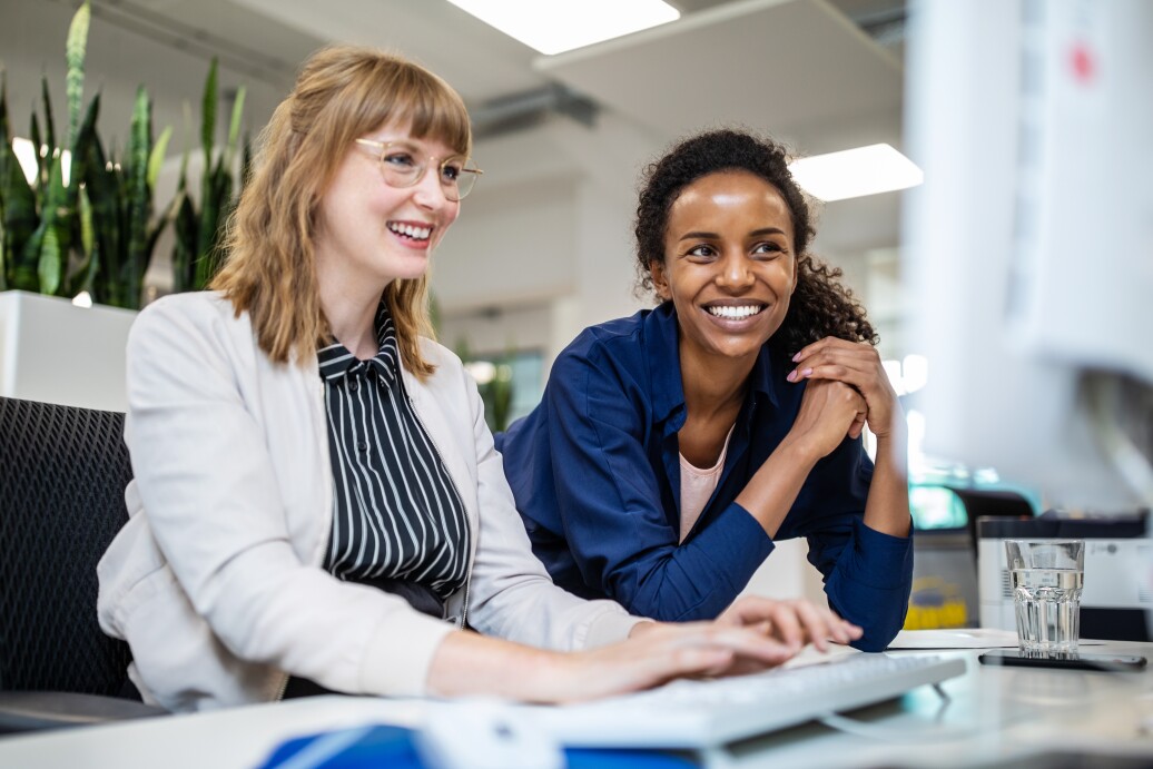 Female colleagues smiling while looking at computer