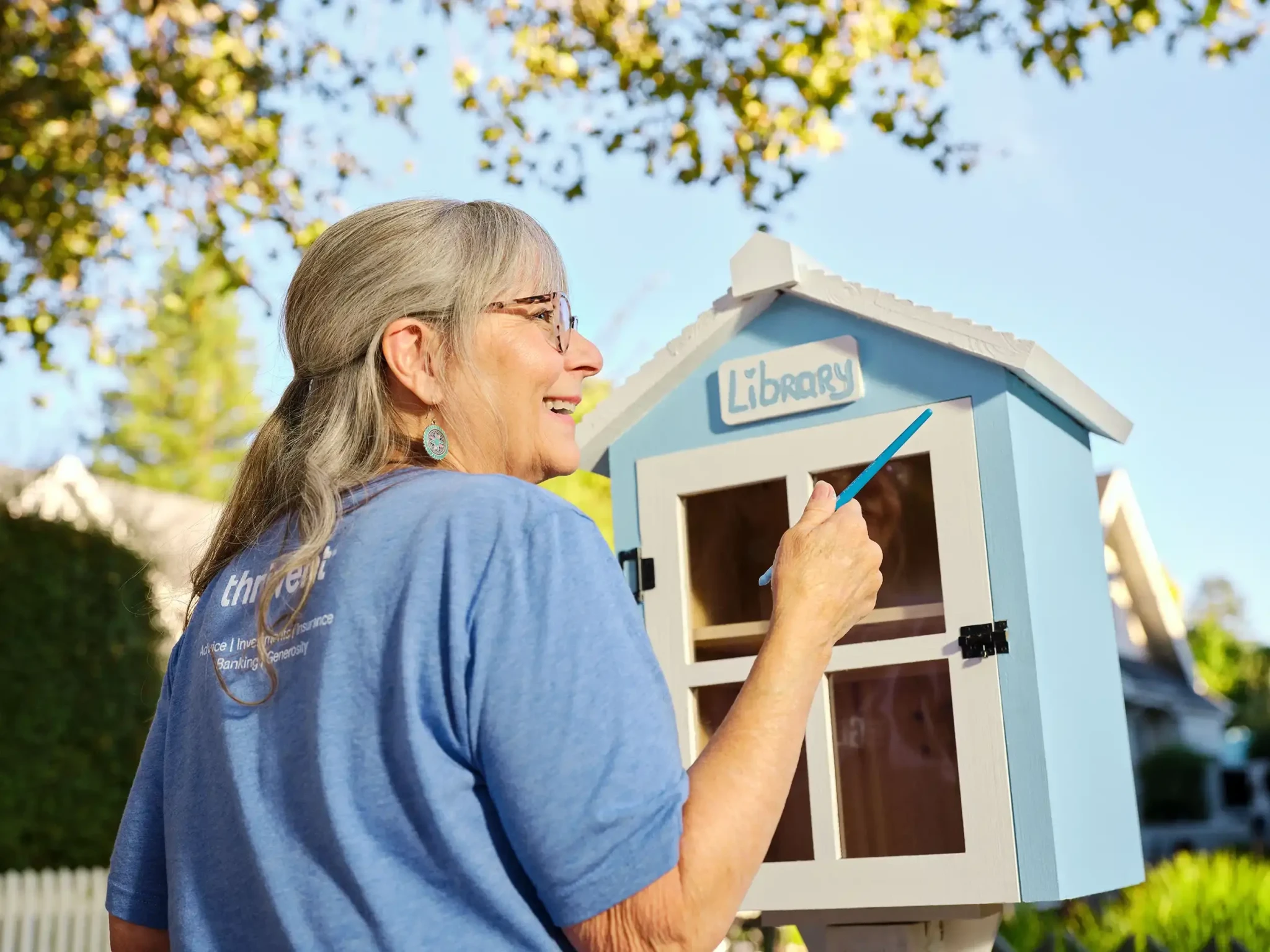 Woman painting a little library