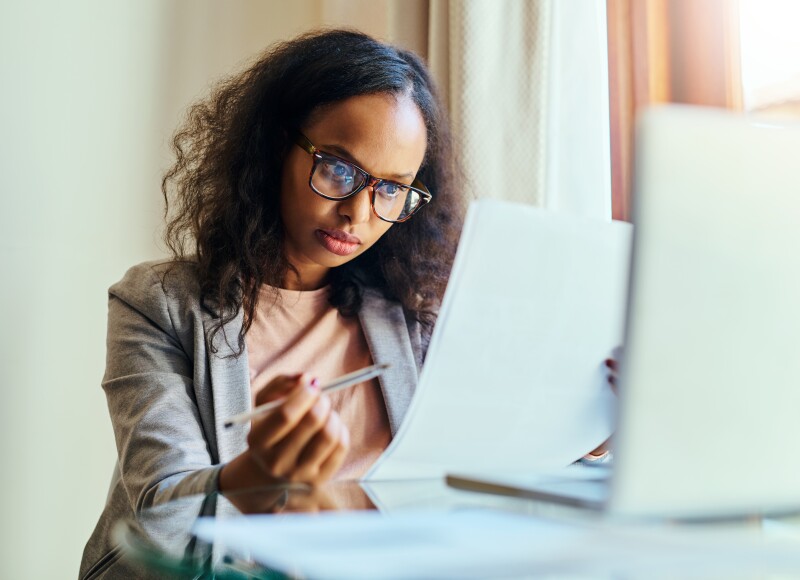 A woman sits at a laptop working through paperwork