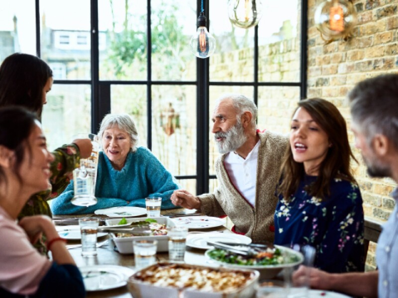 photograph of a people chatting around a dining table in a rustic setting