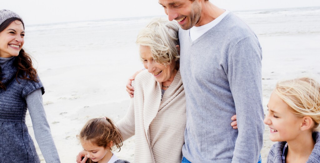 Happy family with grandmother walking on the beach