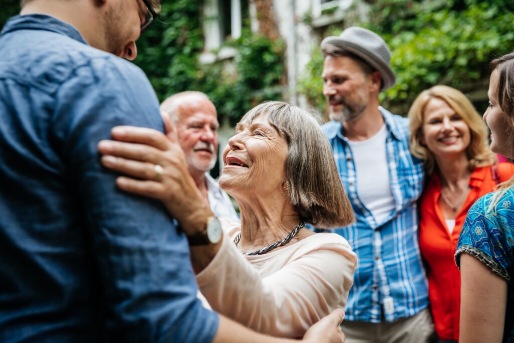 An elderly lady greeting some of her family members in a courtyard before a family meal.