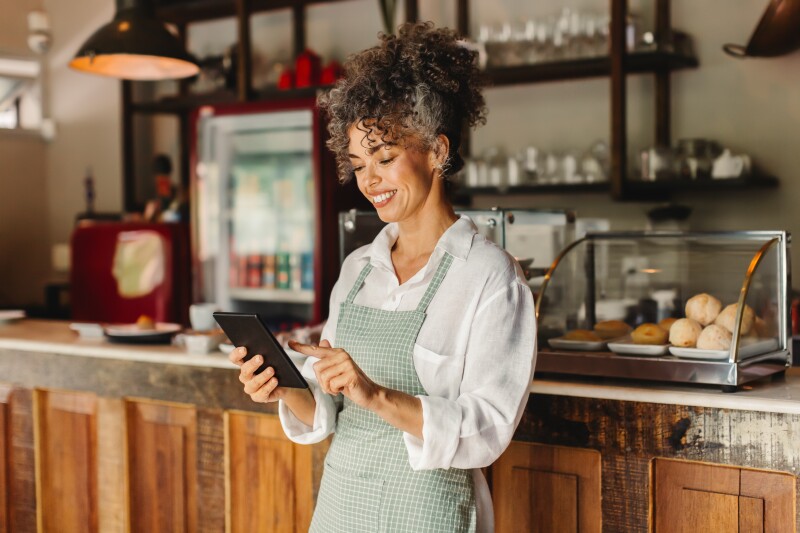 Happy café owner running her business while looking at a digital tablet