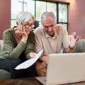 Senior couple using a laptop while going through paperwork at home