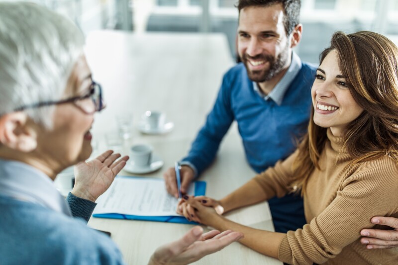 Happy couple talking with their financial advisor in an office meeting.