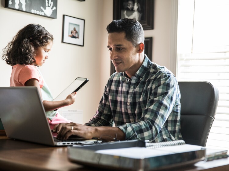 Father working at home with young daughter