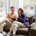 man and woman sitting on couch working on a tablet