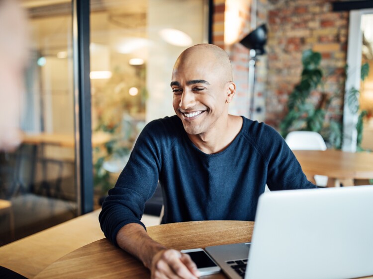 Smiling businessman with laptop at office cafeteria