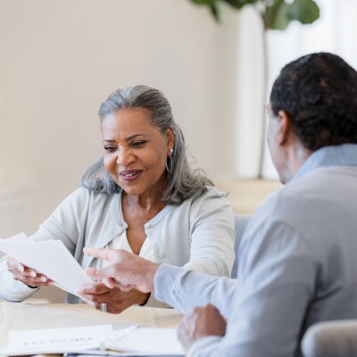 Woman smiles as male financial advisor explains paperwork