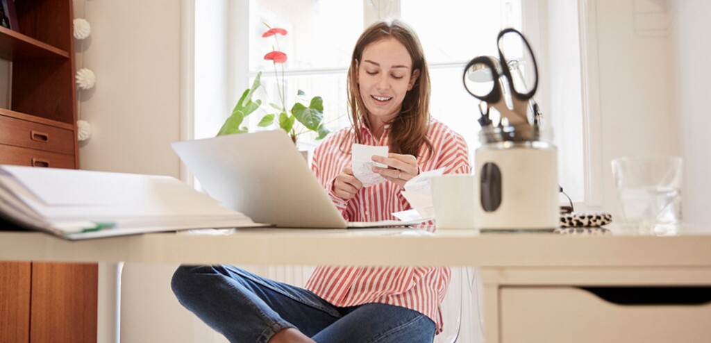 young woman looking at receipts and doing finances on laptop