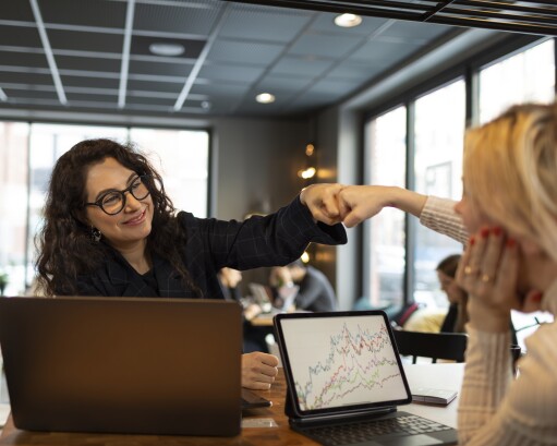 Female coworkers doing fist bump
