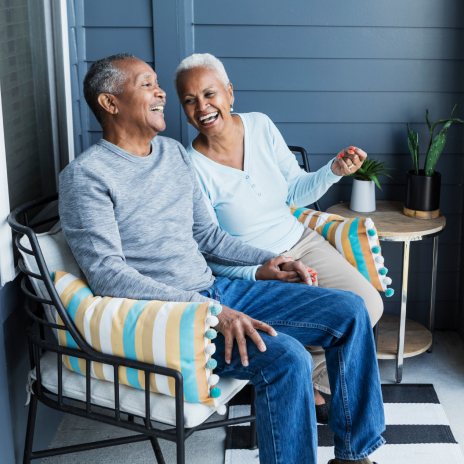 An older couple laughing on a couch together